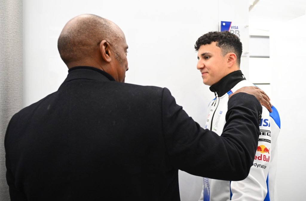MELBOURNE, AUSTRALIA - MARCH 16: Anthony Hamilton with Isack Hadjar of France and Visa Cash App Racing Bulls in the garage during the F1 Grand Prix of Australia at Albert Park Grand Prix Circuit on March 16, 2025 in Melbourne, Australia.