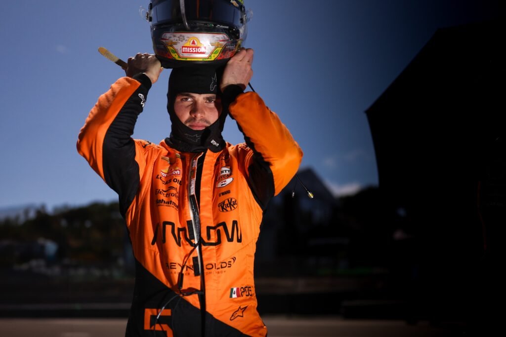 Pato O'Ward donning his helmet ahead of an IndyCar Grand Prix, in his Arrow McLaren suit.